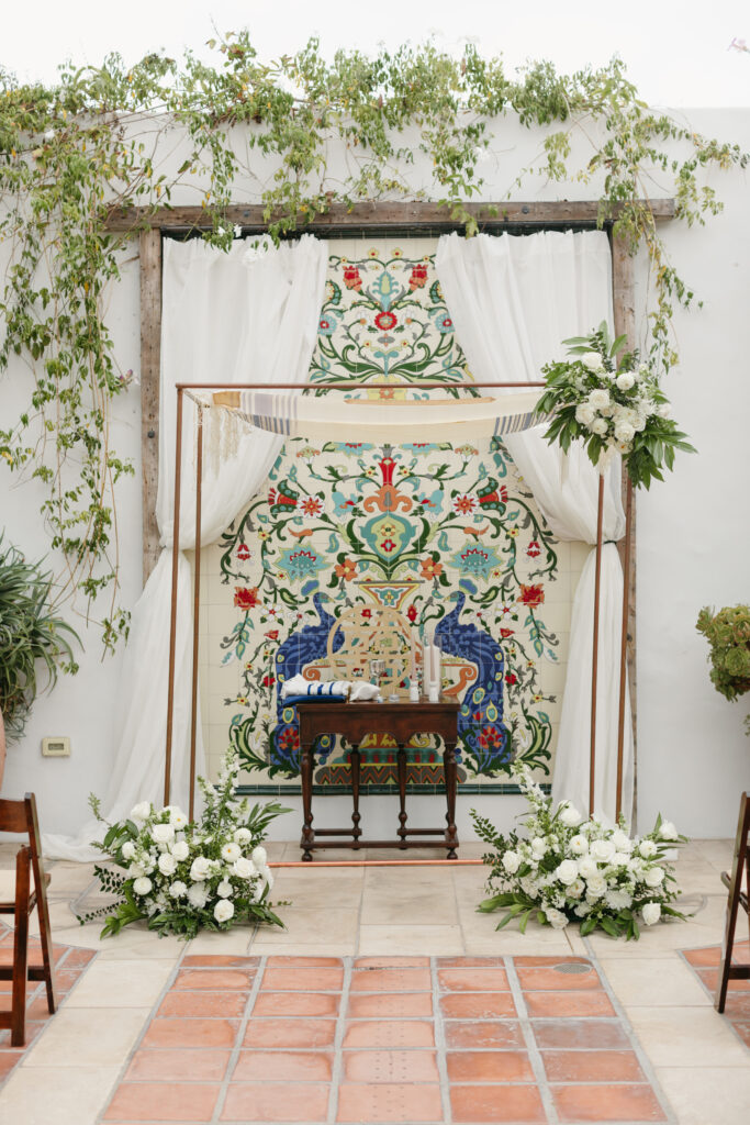 Wedding ceremony at La Ventura Event Center with a copper Chuppah with white flowers and greenery