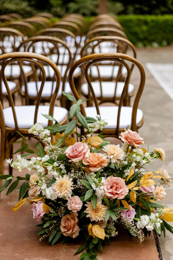 Aisle florals with mauve and peach flowers and greenery at Franciscan Gardens