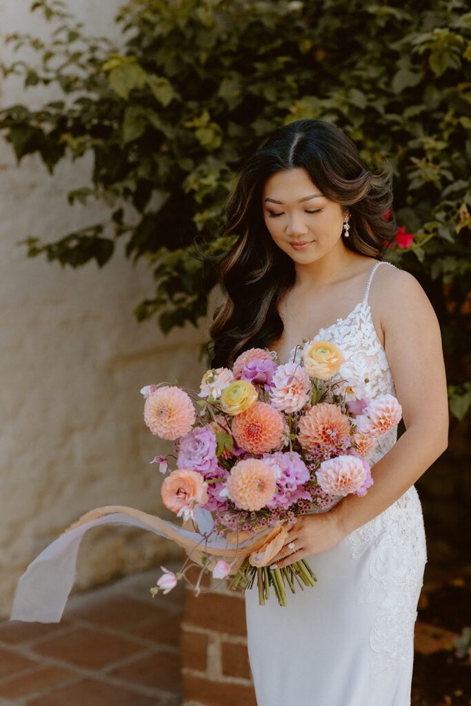 Bride with wavy hair holding a colorful bouquet with long ribbon
