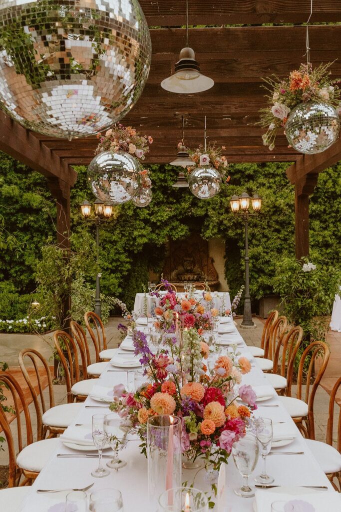disco balls with flowers hanging over a wedding reception table