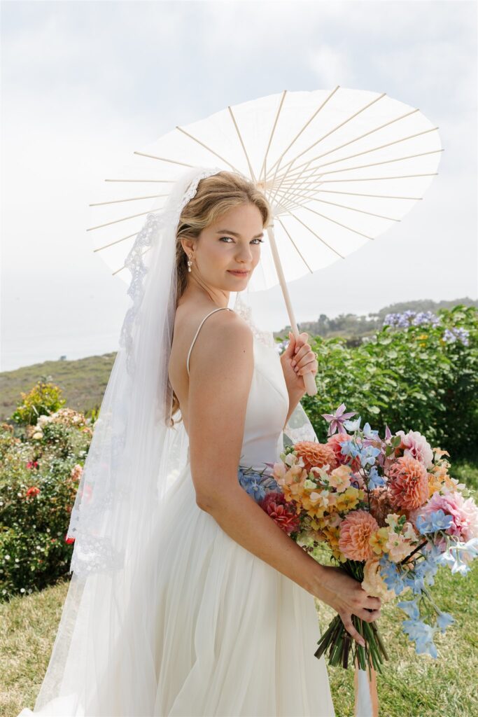 bride holding parasol and colorful summer bridal bouquet