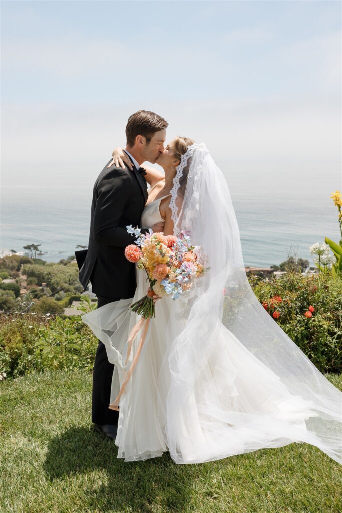 bride and groom with ocean backdrop and bride holding a bouquet designed by urban marigold